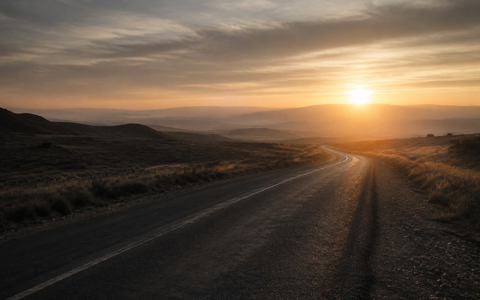 An open road emerging from shadow into warm morning light